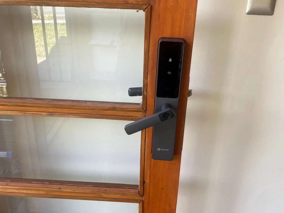 Cerradura inteligente EZVIZ instalada en puerta de madera y vidrio